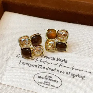 Close-up of asymmetric French vintage stud earrings with amber resin and champagne crystals