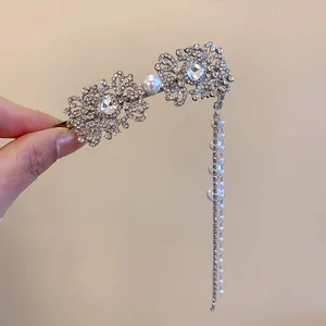 Détail macro d'une pince à cheveux à pompons argentée avec strass et perles