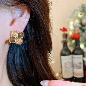 Detail view of vintage-style square stud earrings with champagne and cat's eye stones
