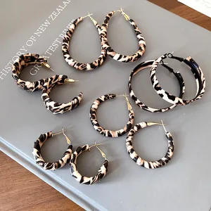 Variedad de pendientes de aro envueltos en cuero con estampado de leopardo y varias formas.