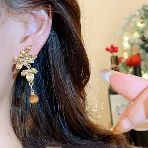 Detailed close-up view of elegant gold floral drop earrings worn on a model's ear