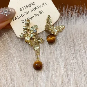 Asymmetrical golden flower and butterfly earrings with brown resin beads and S925 needles.