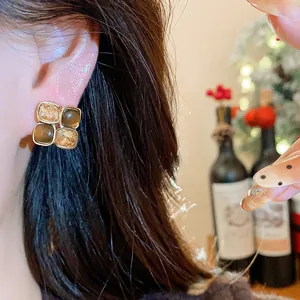 Close-up detail of retro square stud earrings with amber and brown resin stones