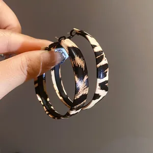 Vista macro de elegantes pendientes de aro en cuero con estampado de leopardo