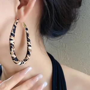 Primer plano de pendientes de aro grandes envueltos en cuero con estampado de leopardo.