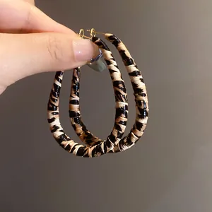 Primer plano de pendientes de aro envueltos en cuero con estampado de leopardo y oro