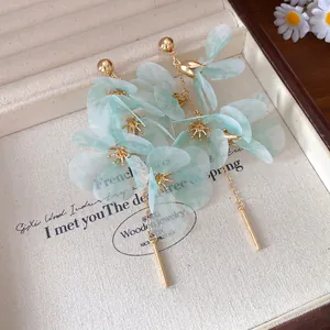 Gros plan d'élégantes boucles d'oreilles fleur vert clair dans un écrin à bijoux.