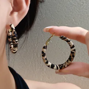 Primer plano detallado de unos pendientes de aro en cuero con diseño de leopardo