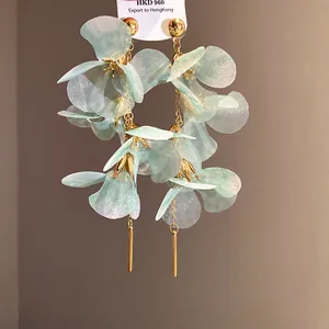 Vue détaillée de boucles d'oreilles fleurs en tissu vert menthe et pompons