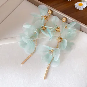 Détail des boucles d'oreilles fleuries vert menthe avec pompons et accents dorés raffinés