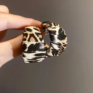 Vista detallada de pendientes de aro de cuero con estampado de leopardo y acabado texturizado