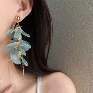 Gros plan sur d'élégantes boucles d'oreilles à pompons en pétales de fleurs vertes