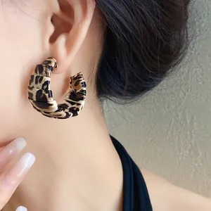 Primer plano de elegantes pendientes de aro en cuero con estampado de leopardo