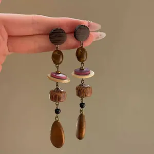 Close-up of asymmetric vintage earrings with earthy tiger eye beads and resin details.