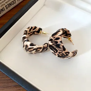 Primer plano de elegantes pendientes de aro envueltos en cuero con estampado de leopardo