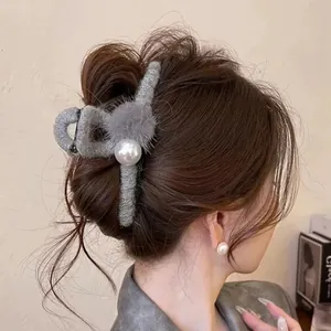 Elegant grey plush hair claw clip with pearl and pom-pom shown on model's hair.