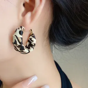 Primer plano de un pendiente de aro con estampado de leopardo usado por una modelo joven