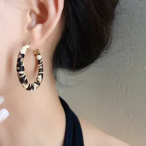 Primer plano de una modelo luciendo unos elegantes aretes de aro forrados en cuero de leopardo.