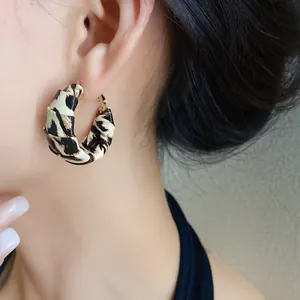 Primer plano de pendientes de aro envueltos en cuero con estampado de leopardo estilo Y2K