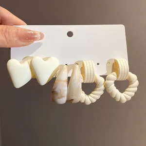 Macro view of retro acrylic marbled C-shaped and heart earring set on white card