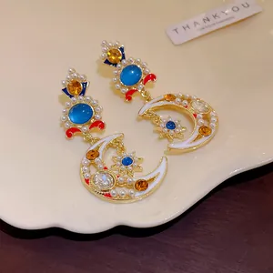 Primo piano di orecchini vintage in stile palazzo con stella, luna in smalto e perle