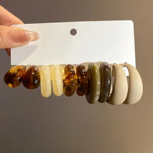 Close-up detail of retro acrylic C-shaped earring set in warm Maillard earthy tones