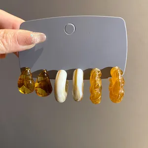 Detailed view of vintage acrylic earring set featuring marbled hoops and amber teardrop studs