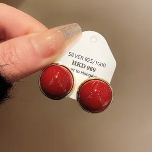 Close-up detail of retro elegant red round stud earrings with silver needles on card
