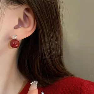 Detail of a vintage red pearl earring with a sparkling zircon stud on ear