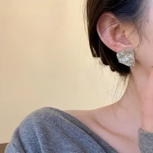 Minimalist irregular silver resin stud earrings with a unique textured foil finish on model