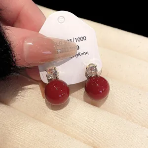 Elegant red pearl drop earrings with sparkling zircon studs shown in close-up detail.