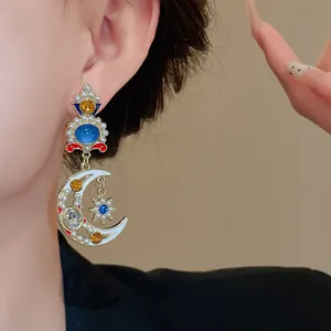 Dettaglio orecchino vintage pendente a mezzaluna e stella con perle e gemme blu lucenti