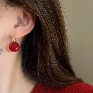 Macro detail showing a vintage deep red pearl ball earring with a gold-tone hoop