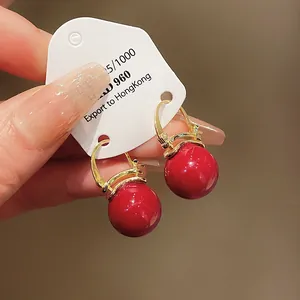Close-up of vintage red pearl earrings with elegant gold hoops on a white jewelry card