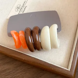 Detail view of acrylic marble C-shaped hoop earrings set in Maillard retro tones