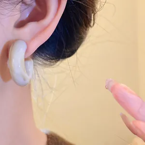 Close-up detail of a marbled acrylic C-shaped earring with retro aesthetic texture