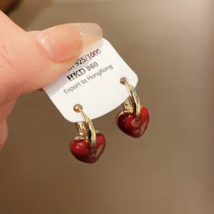 Close-up of vintage-style red heart pendant earrings with gold hoops on a display card.