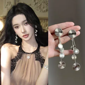 Detailed macro view and worn look of elegant silver sunburst disc tassel drop earrings