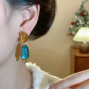 Elegant irregular oval resin drop earrings with gold-tone accents worn by a model