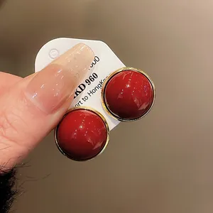 Close-up view of vintage red semi-sphere stud earrings with gold rim on card