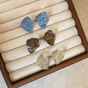 Detailed macro view of three pairs of irregular resin stud earrings in a display box