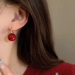 Detail view of a retro style red pearl earring worn on a model's ear