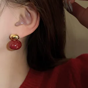 Close-up detail of elegant vintage-style red and gold stud earrings worn by a model