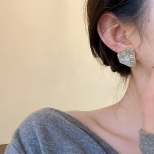 Close-up shot of a minimalist irregular silver-colored resin stud earring worn on a model's ear