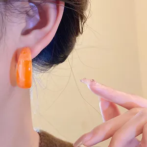 Detailed close-up showing a vintage orange marbled acrylic C-shaped earring on ear