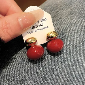 Detailed macro shot of vintage style red and gold stud earrings displayed on a white card