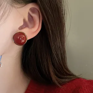 Close-up of elegant vintage red round stud earring worn on model's ear