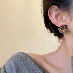 Close-up of a stylish irregular resin stud earring with gold flakes on a model