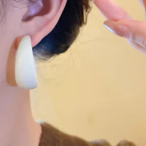Close-up detailed view of a minimalist white acrylic C-shaped hoop earring on ear