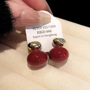 Macro detail of elegant red and gold stud earrings on a beige velvet display